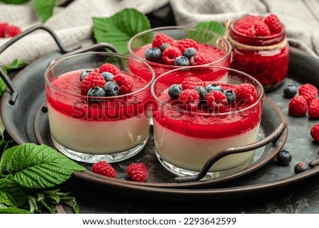 Delicious italian dessert panna cotta with berry sauce on a dark background in small jars. place for text.