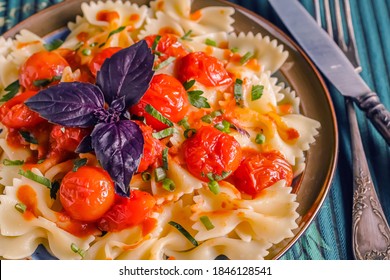 Delicious Italian Pasta With Cherry Tomato Sauce And Purple Basil. In A Plate On A Blue-green, Light Blue Background. Bow Tie Pasta. Close-up.