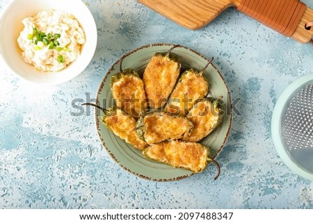 Delicious jalapeno poppers in plate on color background