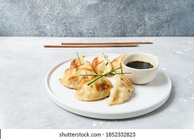 Delicious Japanese gyoza dumplings fried on a white plate with soy sauce
