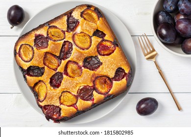 Delicious Juicy Plum Pie In A Round Plate On A White Wooden Background, Square Cake, Top View