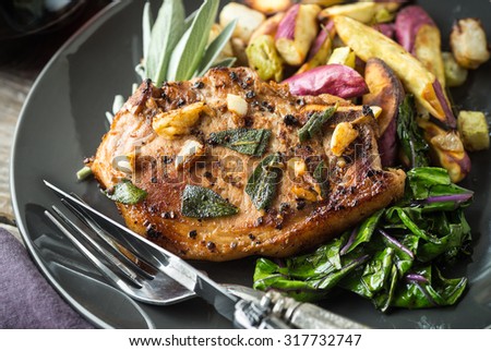 Delicious juicy pork chop with sage, garlic and root vegetables