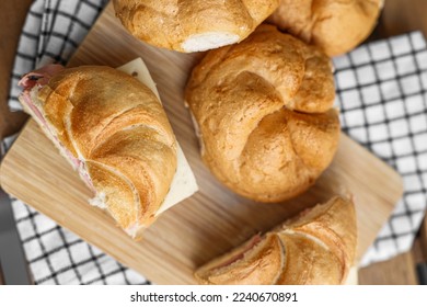 Delicious kaiser rolls with ham and cheese on table