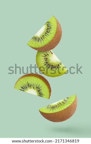 Delicious kiwi slices, flying in the air, isolated on pastel turquoise background