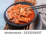 Delicious Korean Cuisine spicy tteokbokki or ttopoki on black plate. 
