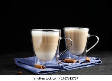 Delicious Latte Macchiato, Cinnamon And Coffee Beans On Grey Table Against Black Background