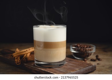 Delicious Latte Macchiato, Cinnamon Sticks And Coffee Beans On Wooden Table