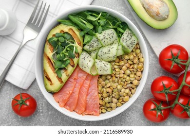 Delicious Lentil Bowl With Salmon, Avocado And Cucumber On Grey Table, Flat Lay