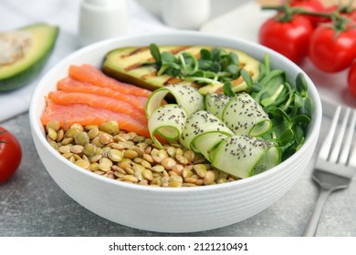 Delicious Lentil Bowl With Salmon, Avocado And Cucumber On Grey Table