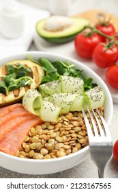 Delicious Lentil Bowl With Salmon, Avocado And Cucumber On Grey Table