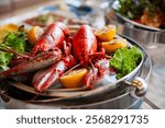 Delicious lobster dish with fresh lobster, lemon, and greens. Lobster served on a platter, and appetizing presentation. Cooked lobster on festive buffet.