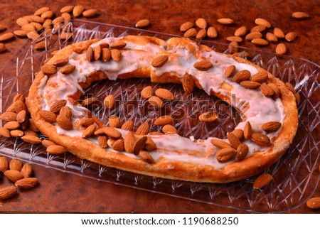 A delicious local favorite almond Danish Kringle with tray on burl surface. 
