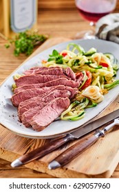Delicious low carbohydrate meal with lean tender sliced roast beef served with a fresh vegetable salad with rustic utensils on a wooden chopping board