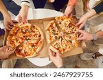 Delicious lunch, snack, fast food. Large group of friends take delicious, fresh and hot slices of pizza from boxes. Top view close-up of men and women