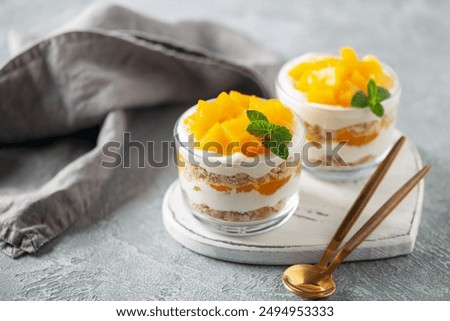 Delicious mango float cake in glasses on wooden board. Filipino sweet cuisine