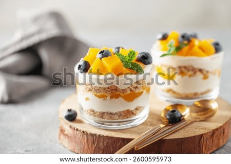 Delicious mango float cake in glasses on wooden board. Filipino sweet cuisine