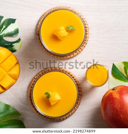 Delicious mango panna cotta mousse pudding with diced mango pulp flesh topping on white table background.