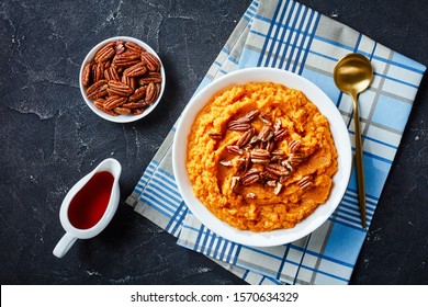 Delicious Mashed Sweet Potato Topped With Pecan Nuts In A Bowl. Maple Syrup In A White Sauceboat On A Concrete Table, Horizontal View From Above, Flatlay
