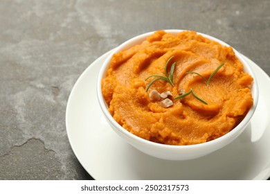 Delicious mashed sweet potatoes with rosemary and nuts in bowl on gray textured table, closeup - Powered by Shutterstock