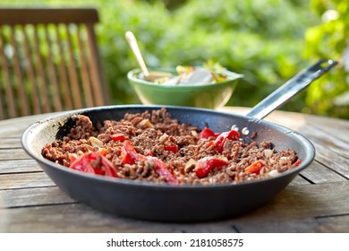 A Delicious Meal With Cooked Beef Meat And Pepper Vegetables. Chili Con Carne Stew Dish Served For Dinner At An Outdoors Restaurant. Texture Detail Of Spicy Homemade Food In A Pan On A Table