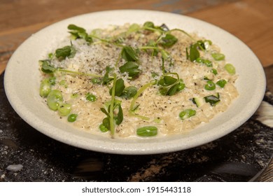 A Delicious Meal Of Courgette, Broad Bean And Pea Risotto, On A Wooden Kitchen Table