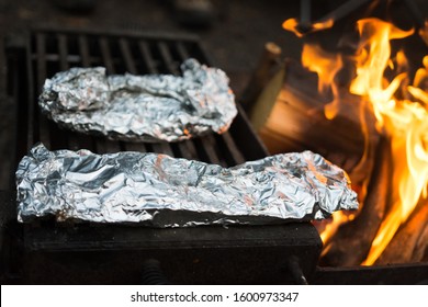 Delicious Meal Wrapped In Tin Foil Cooking Over Fire At Campsite