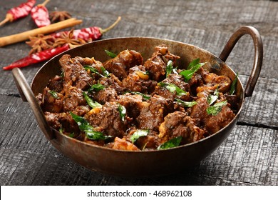 Delicious meat fry in a cast iron cooking vessel on a dark wooden background,Selective focus photograph,