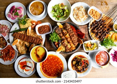 Delicious meat kebab with fresh vegetable salad served with variety of Turkish dishes and appetizers. Top view of assorted Turkish food and meze, tasty and healthy Mediterranean cuisine. - Shutterstock ID 2143433497