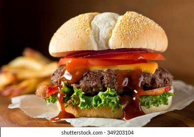 A Delicious Messy Homemade Bacon Cheeseburger With Barbecue Sauce, Lettuce, Tomato, And Onion.