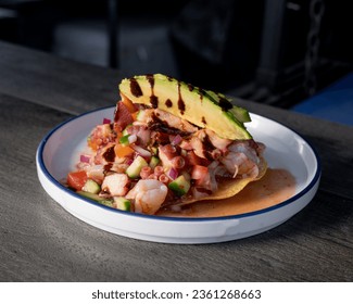 Delicioso camarón de estilo mexicano, tostada de pescado y pulpo, con salsa y aguacate encima, con salsas y preparación tradicional.