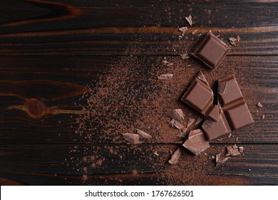 Delicious milk chocolate and cocoa powder on wooden table, flat lay. Space for text - Shutterstock ID 1767626501