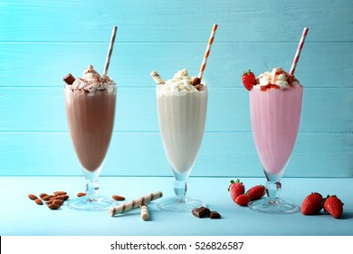 Delicious milkshakes on blue wooden background