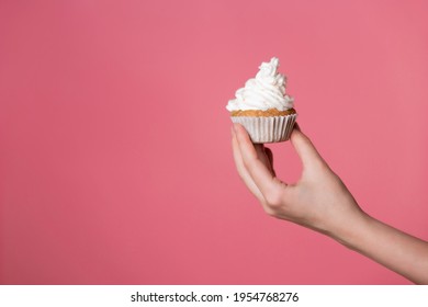 Delicious muffin with cream, homemade cakes. A woman's hand holds a cupcake.