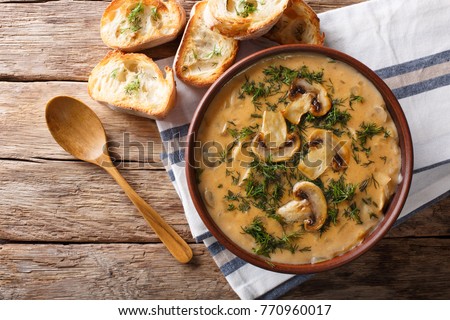Delicious mushroom soup with dill and toast close-up on the table. Horizontal top view from above