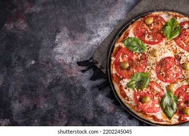 Delicious Neapolitan Style Basil And Tomato Pizza, Decorated With Olives And Oregano On Dark Painted Background, Overhead Shot With Space To Write