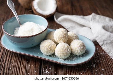 Delicious no bake candy, white chocolate truffles covered in shredded coconut on rustic wooden background