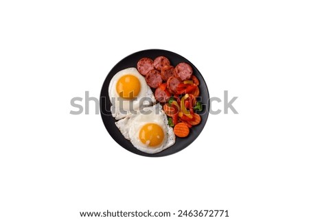 Delicious nutritious breakfast with fried eggs, sausage, steamed vegetables with salt, spices and herbs on a dark concrete background