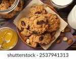 Delicious oatmeal cookies with raisins and nuts served on wooden table, flat lay