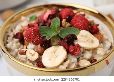 Delicious oatmeal with freeze dried berries, banana, nuts and mint in bowl, closeup - Powered by Shutterstock