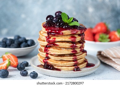 Delicious oatmeal pancakes with berry fruit blueberry strawberry jam dessert topping. Blue background - Shutterstock ID 2172800297