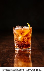 Delicious Old Fashion Cocktail In The Etched Glass With Ice And Orange Slices, Dark Wooden Background, Vertical, Side View