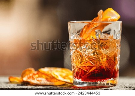 Delicious old fashion cocktail in the etched glass with ice and orange slices, dark wooden background. Shallow dof