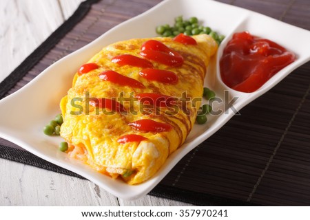 Delicious Omurice omelette with ketchup close-up on a plate. Horizontal