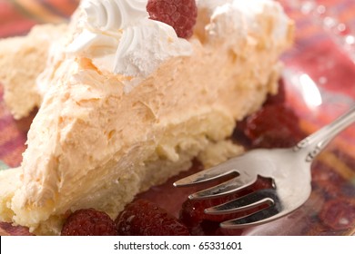 A delicious orange creamsicle pie with chilled raspberries. Shallow Depth pf Field with focus near front of pie, and on frosting top.