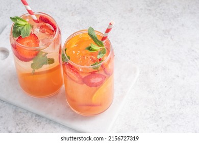 Delicious Orange lemonade with strawberries on grey table, space for text. Fresh summer cocktail