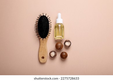Delicious organic Macadamia nuts, cosmetic oil and brush on beige background, flat lay