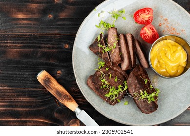 Deliciosos filetes de carne de avestruz. Filete de avestruz sobre fondo rústico negro. Cocina africana. Vista superior.