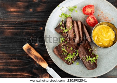 Delicious ostrich meat steaks. Ostrich fillet on black rustic background. African cuisine. Top view.