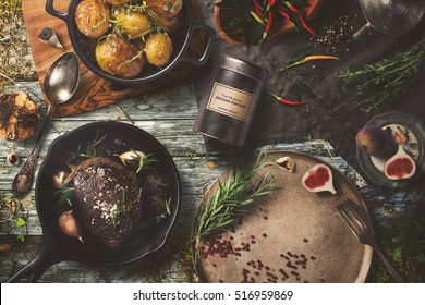 Delicious Outdoor Table With Steak, Baked Potatoes On Dark Background, Top View. Rustic Food Cooking.