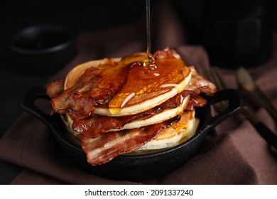 Delicious pancakes with maple syrup and fried bacon on table, closeup